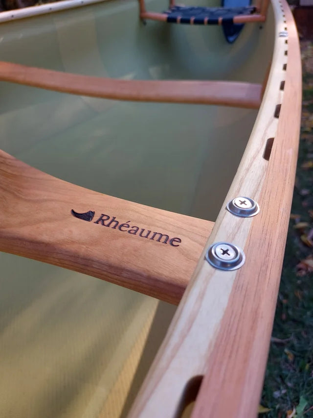 Rheaume Prospector 16'6" Kevlar Canoe with Wood Trim: Adorned with elegant wood gunwales, this version of the Prospector 16'6" not only performs excellently but also exudes a classic charm. The navy blue color with a Kevlar interior finish adds a touch of sophistication, making it a visually striking canoe on any waterway.